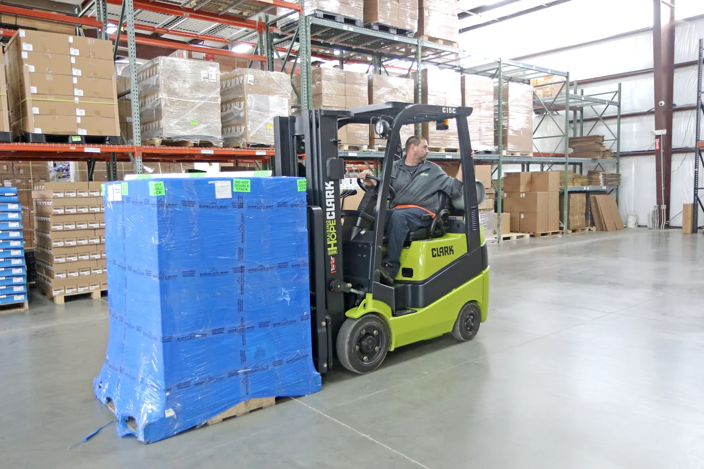 Clark C15C cushion tire forklift moving a wrapped pallet in front of pallet racking in a Baltimore area warehouse